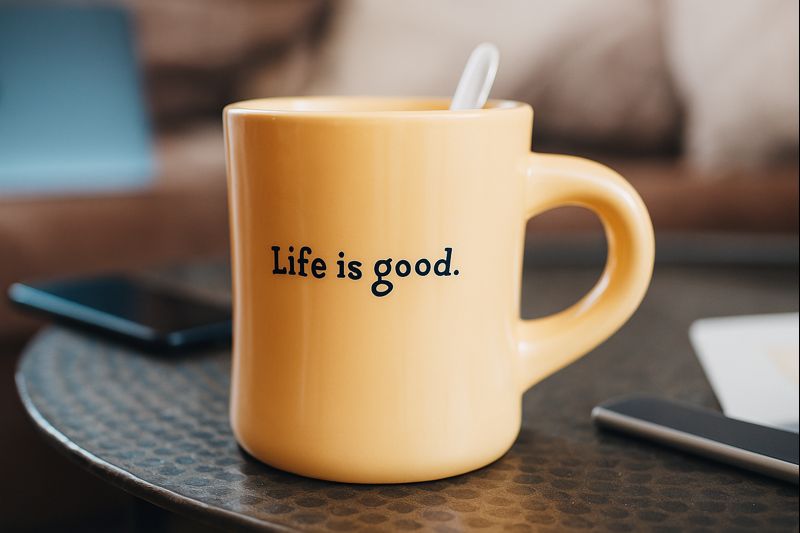 「Life is good. と書かれたマグカップがテーブルの上に置かれている写真」