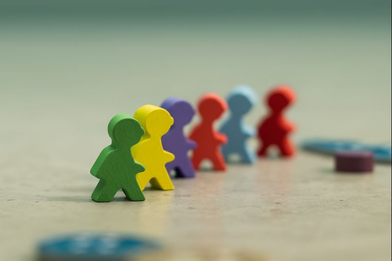 色の異なる人型の木製コマが一列に並んでいる写真