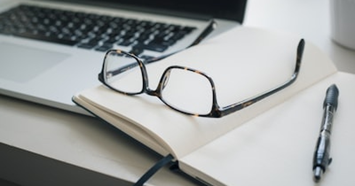 仕事を途中で切り上げる時間管理をイメージした、ノートと眼鏡とペンのある作業机